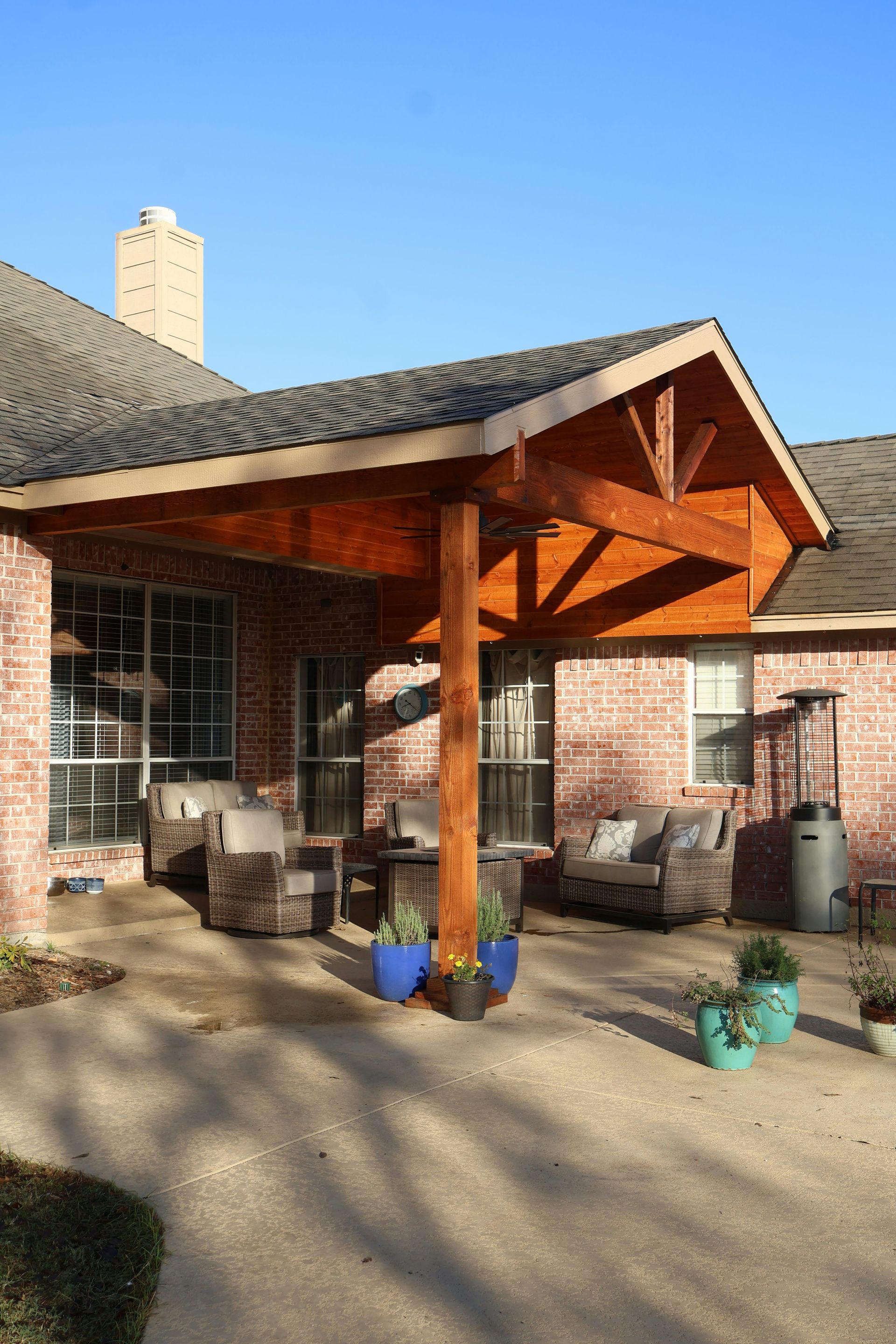Brick house with wooden covered patio and outdoor furniture.
